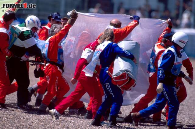 Foto zur News: Die Streckenposten erkennen den Ernst der Lage und schirmen neugierige Fotografen und TV-Kameras mit einem großen Tuch ab. In diesen Momenten verliert Schumacher das Bewusstsein.