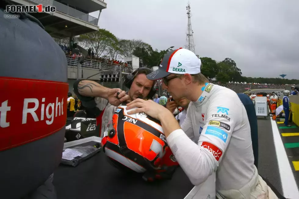 Foto zur News: Vor dem Start noch Rumgefummel am Helm. Der Gummi-Trinkschlauch war nämlich zu lang, und das ist unangenehm, wenn der Helm erstmal auf dem Kopf ist. Also schnipselten Hülkenberg und sein Physio das noch vor dem Start zurecht.