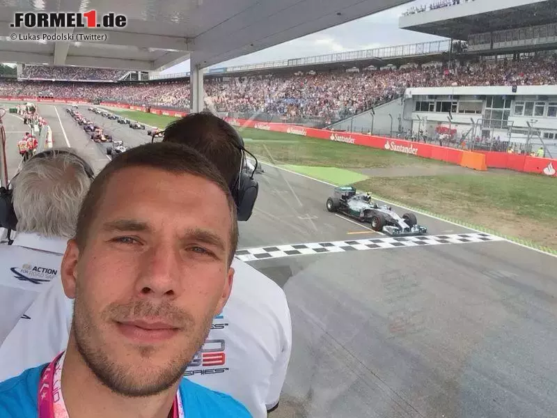 Foto zur News: Als Fußball-Weltmeister darf man alles: Lukas Podolski beim Start im Tower der Rennleitung. Im Hintergrund startet Charlie Whiting gerade den Grand Prix.