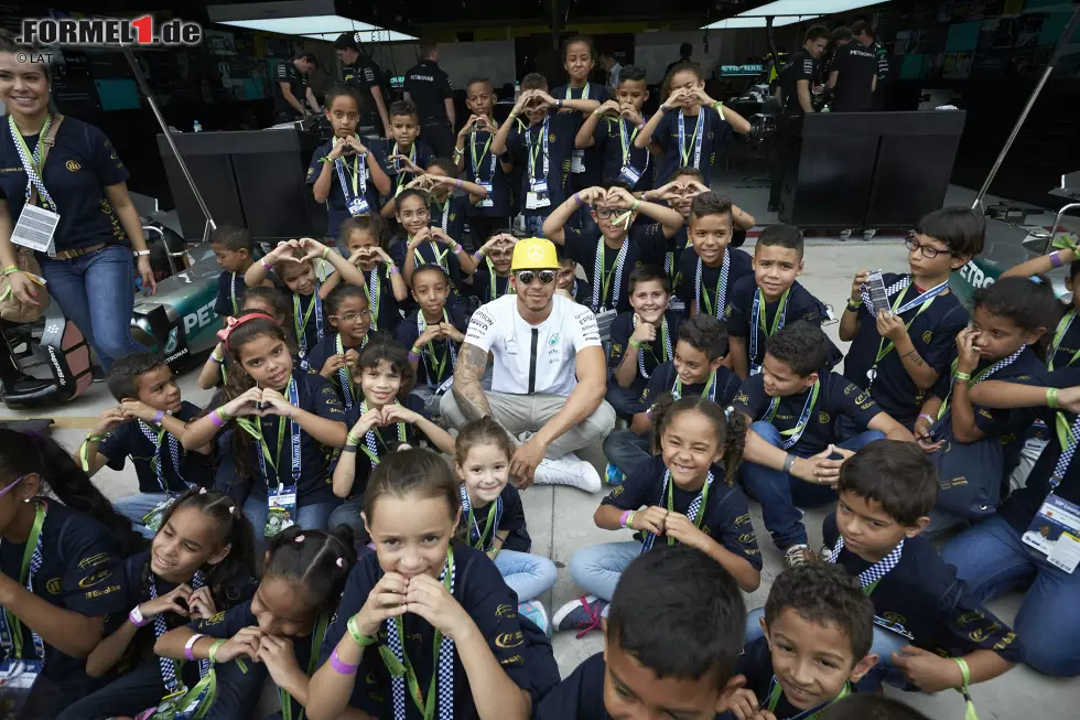 Foto zur News: Immerhin: Beim Fotoshooting mit den brasilianischen Kids wirkt Hamilton schon wieder deutlich fitter als beim Termin bei Madame Tussauds eine Woche zuvor. Und, sind wir mal ehrlich: Die Kinder in Sao Paulo sind auch etwas lebhafter als die Wachsfiguren in London.