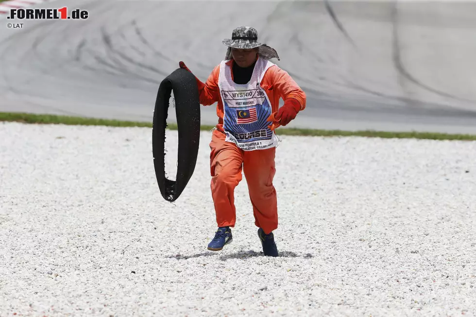 Foto zur News: Tapferer Einsatz dieses Streckenpostens: Nach dem Malheur in der ersten Runde bringt er die zerfetzte Lauffläche von Kimi Räikkönens Pirelli-Reifen in Sicherheit.