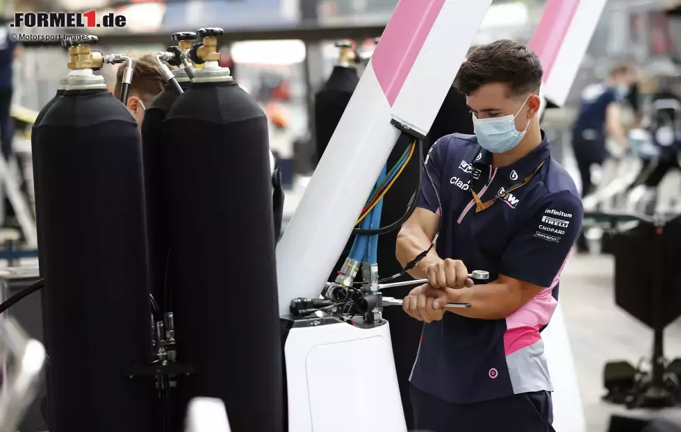 Foto zur News: ... und an den Arbeitsplatz in den Boxen, wo - mit Mundschutz - die Vorbereitungen für das Rennwochenende getroffen werden.